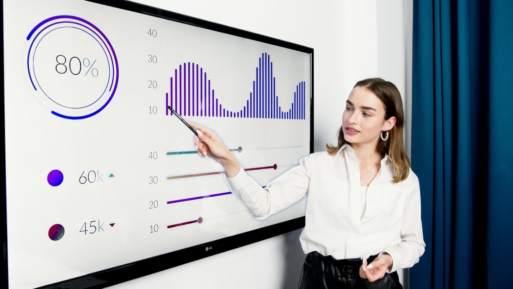 A Concluding photo showing a woman presenting a dashboard that has valuable and standardized metrics, the culmination of the democratization of data. 